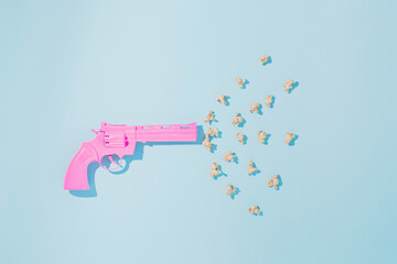 Pink pistol shoots popcorns on pastel blue background. Candy colors. Minimal concept of non-violence and peaceful conflict resolution. Flat lay.