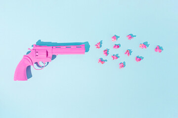 Pink pistol shoots popcorns on pastel blue background. Candy colors. Minimal flat lay concept of non-violence and peaceful conflict resolution. 