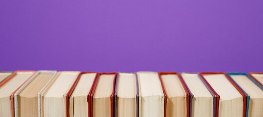 Composition with vintage old hardback books, diary, fanned pages on wooden deck table and colored background. Books stacking. Back to school. Copy Space. Education background.