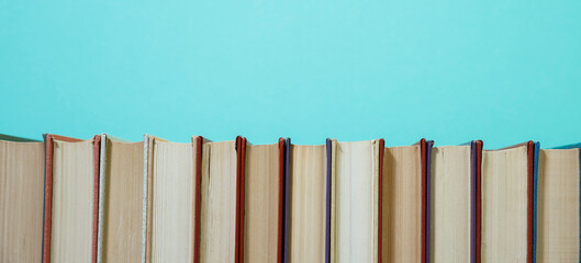 Composition with vintage old hardback books, diary, fanned pages on wooden deck table and colored background. Books stacking. Back to school. Copy Space. Education background.