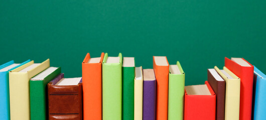 Composition with vintage old hardback books, diary, fanned pages on wooden deck table and colored background. Books stacking. Back to school. Copy Space. Education background.