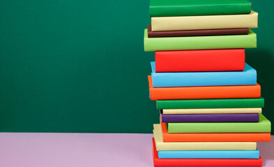 Composition with vintage old hardback books, diary, fanned pages on wooden deck table and colored background. Books stacking. Back to school. Copy Space. Education background.