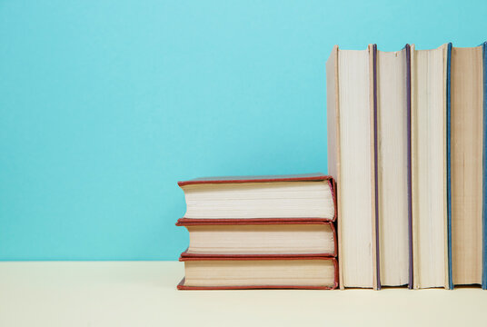 Composition with vintage old hardback books, diary, fanned pages on wooden deck table and colored background. Books stacking. Back to school. Copy Space. Education background.