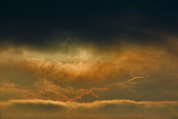 Fototapeta na wymiar dark storm clouds covering golden clouds floating on the twilight horizon.