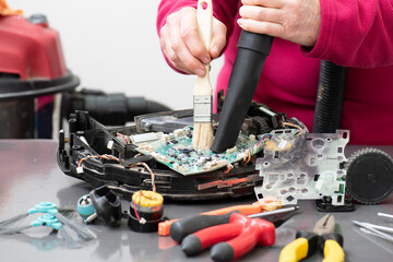 Manos con una aspiradora limpiando un robot de limpieza desmontado