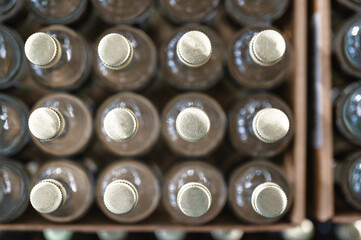 Glass bottles of vodka closed with golden caps in workshop