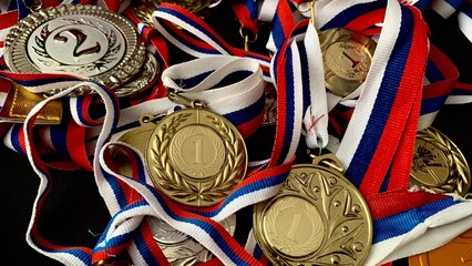 Gold, silver, bronze medals and cups on a black background. A large number of significant awards...