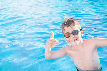 Healthy lifestyle. Active, happy nine years old child (boy) in sport goggles showing thumbs up on...