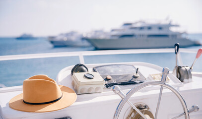 Travel hat lies on steering wheel of modern luxury yacht, concept banner trip on sea, boat rental