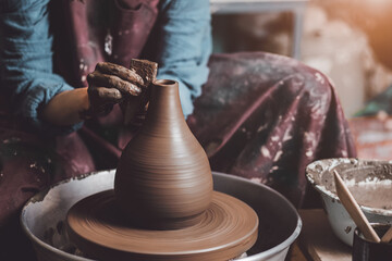Woman hands working on pottery wheel and making a pot.