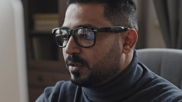 Close up shot of middle eastern businessman in glasses talking on online video call on computer