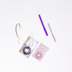 90s Nostalgia. Cassette tape and purple pencil levitating on a white background with shadow. Mangled tape. Retro concept.