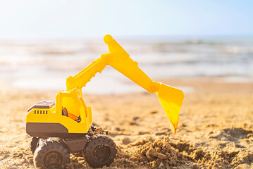 Toy excavator on the beach with copy space