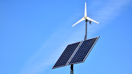 Obraz premium Solar panel and wind turbine against blue sky
