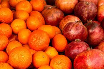 Red ripe pomegranates and tangerines on the counter in the store.
