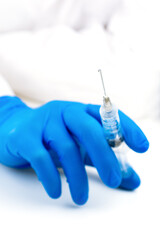Hand in blue glove holding syringe on white. Syringe with sharp needle in hand. Medical treatment concept. Medicare concept. Vaccination concept.