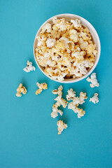 Spilled popcorn on blue background. Movie night concept. Copy space for text