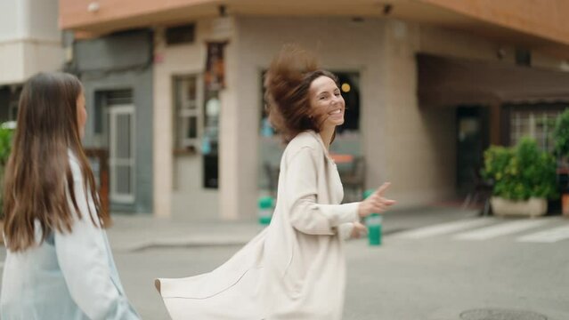 Mother and daughter smiling confident dancing at street