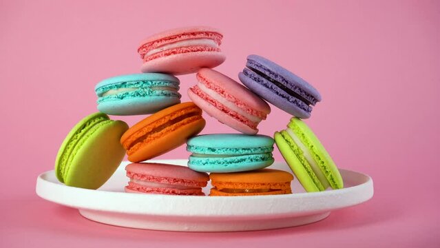 Delicious colorful french macaroons on white plate. Pink background. Zoom-in.