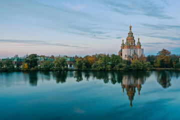Fototapeta na wymiar Olga's Pond and the Cathedral of Peter and Paul in Peterhof at sunset, the reflection of the sky and trees in the water, a church with domes, a photo for a postcard