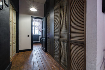 long corridor in interior of entrance hall of modern apartments with doors, cabinets, shelves and a mirror