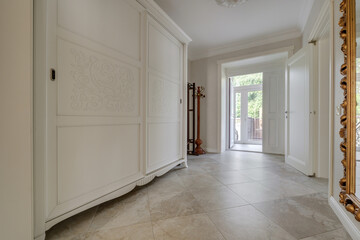 long corridor in interior of entrance hall of modern apartments with doors, cabinets, shelves and a mirror