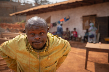 Portrait of an african man with Down syndrome is in an African village.