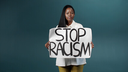 An attractive african lady is showing a poster, calling on everyone to stop racism and moving away