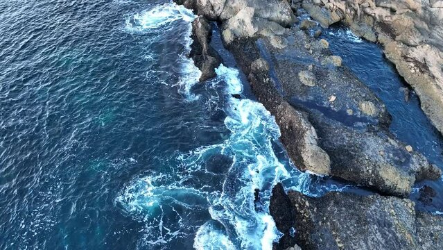 Aerial view of waves and clifs. Sea waves breaking over rocks. Waves splashing on rocks, aerial view of drone.