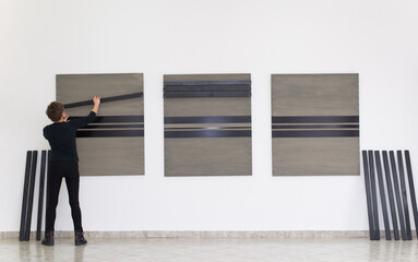 Woman artist assembling modern art piece on the art gallery wall. 