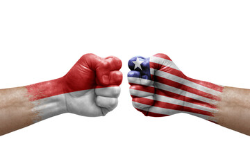 Two hands punch to each others on white background. Country flags painted fists, conflict crisis concept between indonesia and liberia