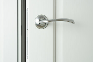 Slightly open white wooden interior door with handle and magnetic locking pawl.