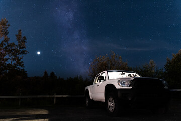 Fototapeta na wymiar Generic white pickup truck under starry night sky Milky Way band. Vehicle truck in the outdoors nature background