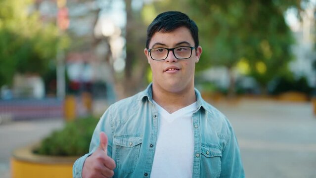 Down syndrome man smiling confident doing ok sign with thumb up at park