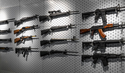 Collection of rifles and carbines. Various firearms hang on special mounts on the wall. Weapon back - obrazy, fototapety, plakaty