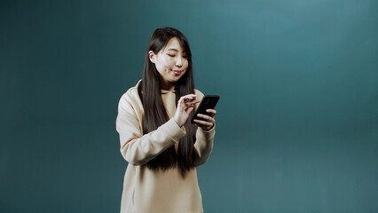 A handsome asian lady is using a phone and chatting with her friend 