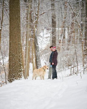 PITTSBURGH, PA, USA - FEBRUARY 5TH 2022: A middle-aged father is hiking with his teenage daughter and their dog in the frozen winter forest covered in snow after an ice rain hit Pennsylvania.