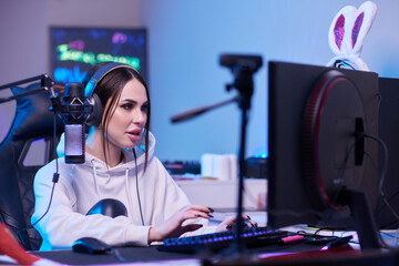 Happy woman putting on headphones and playing computer game. Female gamer in glasses sitting and looking at computer monitor. © Евгений Вершинин