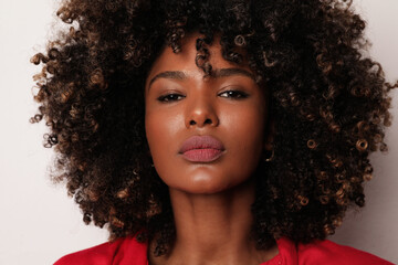 Headshot of African American young woman with curly hair over white background.