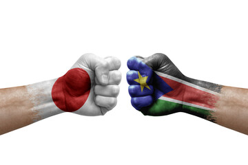 Two hands punch to each others on white background. Country flags painted fists, conflict crisis concept between japan and south sudan