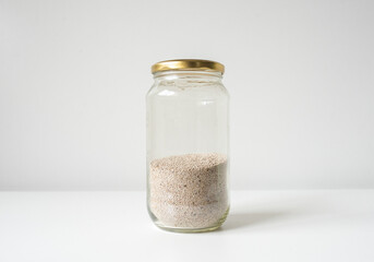 Close up of chia seeds in glas jar against white background (selective focus)