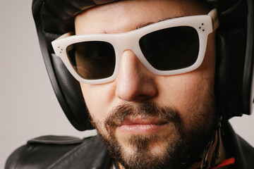 Fototapeta premium Close-up headshot of bearded biker man posing in leather jacket and sunglasses.