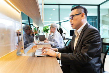 Asian businessman in formal suit working in modern luxury coworking space office using computer for business usage