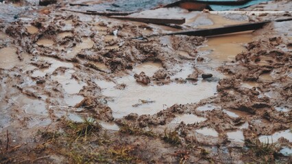 Rain Water Puddles Formed in Deep Footprints Left in Wet Muddy Ground on Messy Construction Site	
