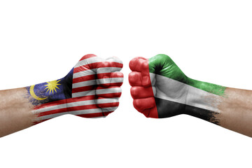 Two hands punch to each others on white background. Country flags painted fists, conflict crisis concept between malaysia and united arab emirates