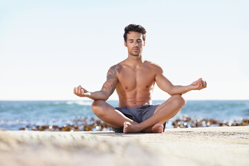 Fototapeta na wymiar Seeking enlightenment in nature. A young man meditating next to the ocean.