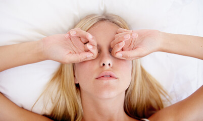 She needs more sleep. A beautiful young woman rubbing her eyes while waking up in the morning.