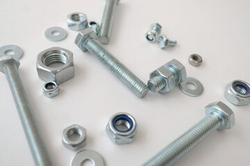 Nuts, screws, bolts are on a white background. Construction tools and parts.