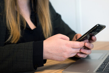 Closeup of hands of woman using smartphone at the office