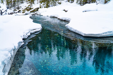 Snow covered blue river in winter with clear transparent water 